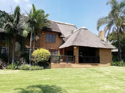 a large brick house with a thatched roof at MixoSunrise Guesthouse & Spa in Pretoria