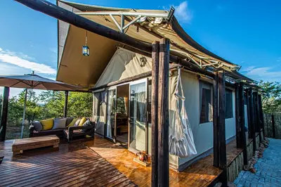 a house with a deck with a couch and an umbrella at Mountain View Safari Lodge in Hoedspruit