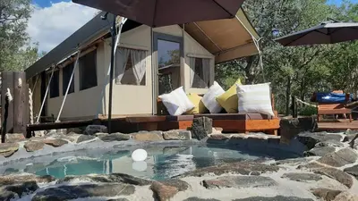 a tiny house with a swimming pool and an umbrella at Mountain View Safari Lodge in Hoedspruit