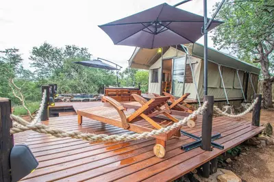 a house with a deck with chairs and an umbrella at Mountain View Safari Lodge in Hoedspruit