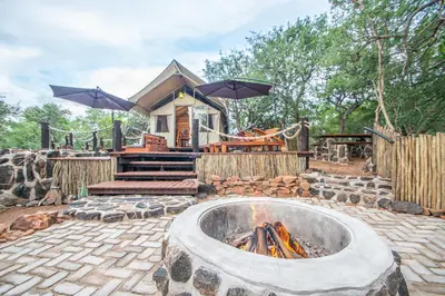 a fire pit in front of a house with umbrellas at Mountain View Safari Lodge in Hoedspruit