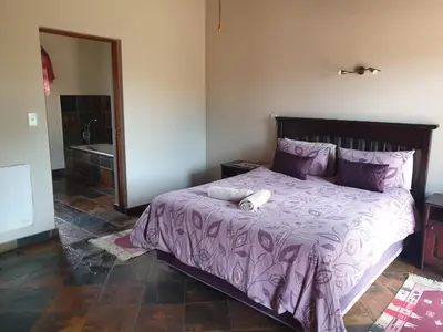 a bedroom with a bed with a purple comforter at Makhato Bush Lodge 86 in Bela-Bela