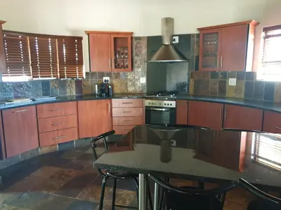 a kitchen with wooden cabinets and a table with chairs at Makhato Bush Lodge 86 in Bela-Bela