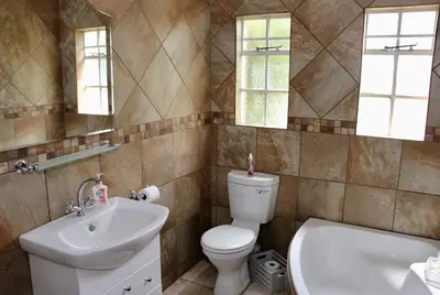 a bathroom with a toilet and a sink and a tub at Lakeview Cottages in Haenertsburg