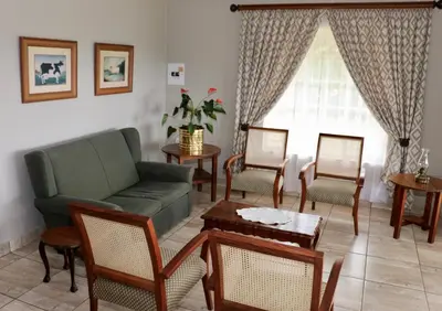 a living room with a couch and chairs and a window at Lakeview Cottages in Haenertsburg