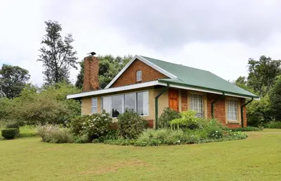 a house with a green roof on a yard at Lakeview Cottages in Haenertsburg