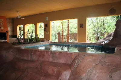 a large pool in a house with a rock wall at Kiburi Lodge @ Kruger, a secluded Bushveld getaway in Marloth Park