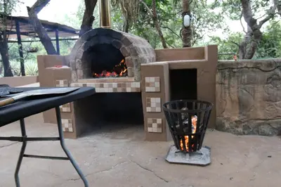 a outdoor pizza oven with a table and a table at Kiburi Lodge @ Kruger, a secluded Bushveld getaway in Marloth Park
