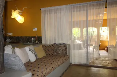 a living room with a couch and a window at Kiburi Lodge @ Kruger, a secluded Bushveld getaway in Marloth Park