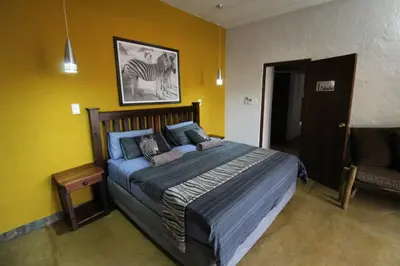 a bedroom with a large bed in a yellow wall at Kiburi Lodge @ Kruger, a secluded Bushveld getaway in Marloth Park