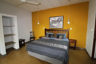 a bedroom with a bed and a yellow wall at Kiburi Lodge @ Kruger, a secluded Bushveld getaway in Marloth Park