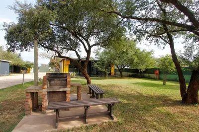 a park with two benches in a park with trees at SleepOver Komatipoort in Komatipoort