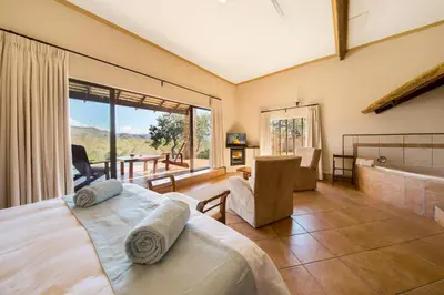 a bedroom with a bed and a tub and a window at Lions Rock Rapids - Lodge in Hazyview