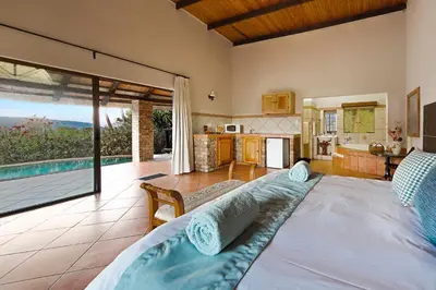 a bedroom with a bed and a kitchen with a view at Lions Rock Rapids - Lodge in Hazyview