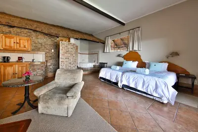 a bedroom with two beds and a chair and a table at Lions Rock Rapids - Lodge in Hazyview