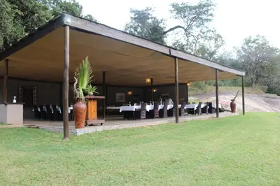 a tent with a table and chairs in a field at Lions Rock Rapids - Lodge in Hazyview