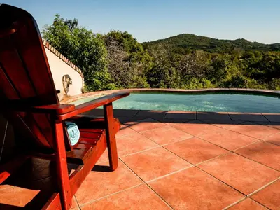 a wooden chair sitting next to a swimming pool at Lions Rock Rapids - Lodge in Hazyview