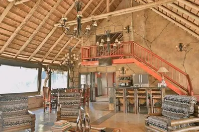 a large room with chairs and a staircase in a building at Tshukudiba Game Lodge in Tom Burke