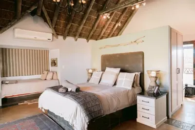 a bedroom with a large bed and a couch at Tshukudiba Game Lodge in Tom Burke
