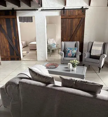 a living room with a couch and two chairs and a table at Le Soleil in Graskop