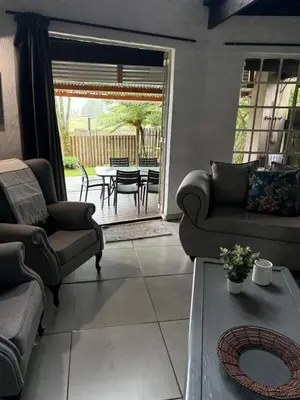 a living room with couches and a table and a patio at Le Soleil in Graskop