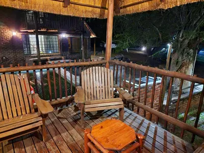 two wooden chairs and a table on a deck at Carpe Diem in Marloth Park