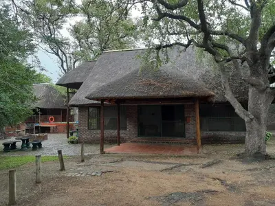 a small brick building with a thatched roof at Carpe Diem in Marloth Park