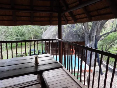 a wooden deck with a bench on a porch at Carpe Diem in Marloth Park