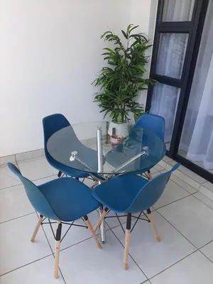 a glass table with two blue chairs and a laptop on it at The Blyde Crystal Lagoon penthouse in Pretoria