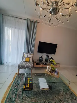 a living room with a glass table and a tv at The Blyde Crystal Lagoon penthouse in Pretoria