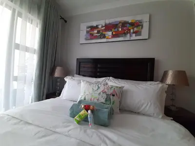 a bed with white pillows and bottles on it at The Blyde Crystal Lagoon penthouse in Pretoria