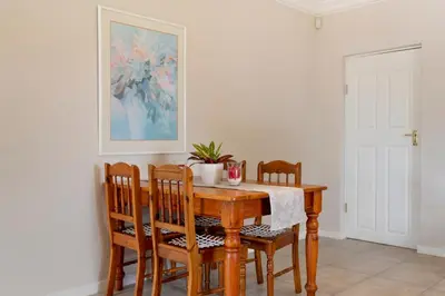 a dining room table and chairs with a painting on the wall at Ruebys Apartment 202 in Dullstroom