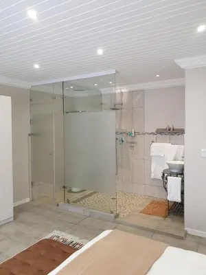 a glass shower in a bathroom with a sink at Ruebys Apartment 202 in Dullstroom