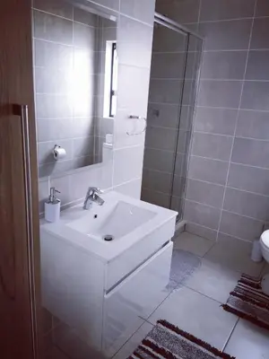 a white bathroom with a sink and a shower at The Blyde in Pretoria