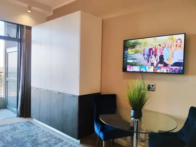 a living room with a table and a tv on the wall at The Residence Studio - Menlyn Maine in Pretoria