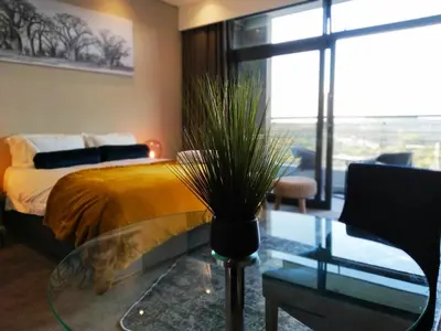 a bedroom with a bed and a glass table with a plant at The Residence Studio - Menlyn Maine in Pretoria