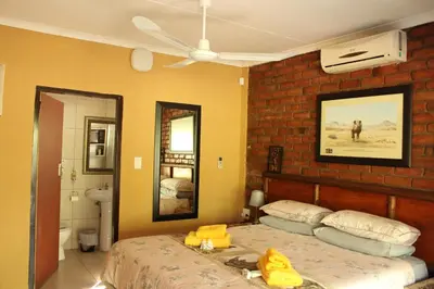 a bedroom with a bed and a brick wall at Umhlanga Kruger in Marloth Park