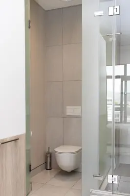 a bathroom with a toilet and a glass shower at Menlyn Apartment in Pretoria