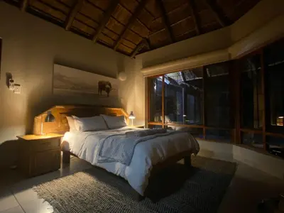 a bedroom with a bed and a large window at Twiga Lodge Mabalingwe in Bela-Bela