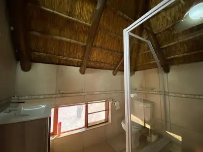 a bathroom with a toilet and a window at Twiga Lodge Mabalingwe in Bela-Bela
