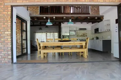 a dining room with a table and a kitchen at Coga Cottage - Marloth Park in Marloth Park
