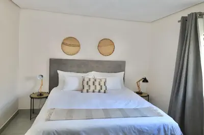 a bedroom with a large white bed with two lamps at Together Lifestyle Resort in Malamulele