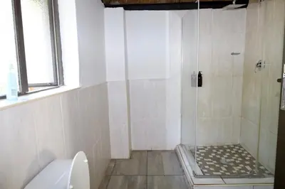 a bathroom with a shower with a toilet and a window at Together Lifestyle Resort in Malamulele