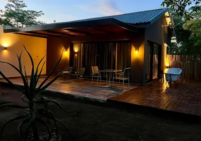 a house with a wooden deck with chairs and a table at Together Lifestyle Resort in Malamulele