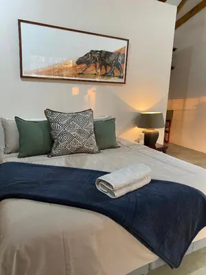 a large bed with a blue blanket on top of it at Murchison View Cottage in Gravelotte