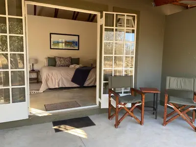 a bedroom with a bed and a table and chairs at Murchison View Cottage in Gravelotte