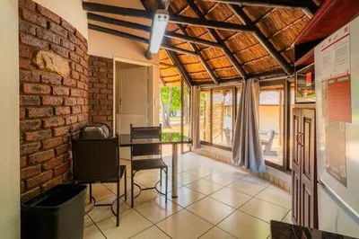 a dining room with a brick wall and a table and chairs at ATKV Eiland Spa in Letsitele
