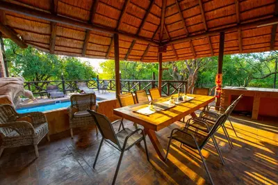 a table and chairs on a porch with a pool at Adventure Bush House in Marloth Park