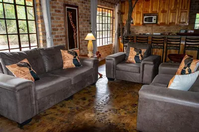 a living room with a couch and two chairs at Adventure Bush House in Marloth Park