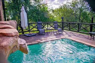 a pool with an umbrella next to a fence at Adventure Bush House in Marloth Park